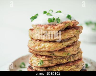 Zucchini-Krapfen. Traditionelle Zucchini fritters im Stapel auf weißem Hintergrund. Vegetarische Zucchini-Pfannkuchen oder Fritten mit grünen Zwiebeln und Stockfoto