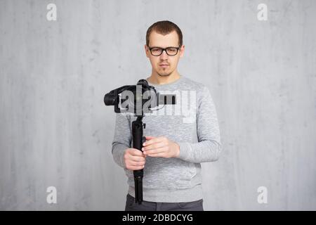 Professioneller Videofilmer mit dslr-Kamera auf 3-Achsen-Gimbal Über grauem Betonwand Hintergrund mit Kopierraum Stockfoto