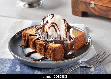 Ein Stück Gourmet-Pfund-Kuchen mit Vanille-Eis und Schokoladensauce gekrönt. Stockfoto