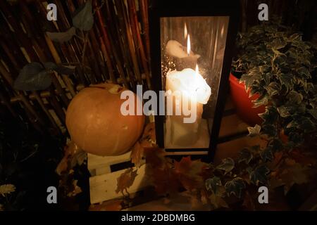 Street Halloween Deko mit Kürbissen, Blumentöpfen, Landzaun und großer Kerze Stockfoto