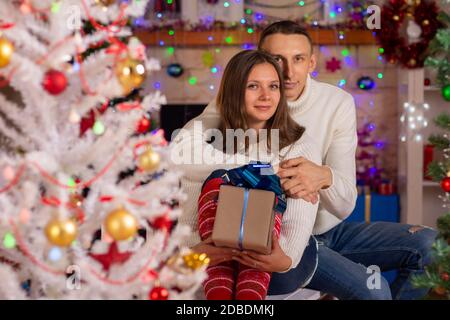 Ein Paar in der Liebe mit Geschenken in der Nähe eines Weihnachtsbaums Stockfoto