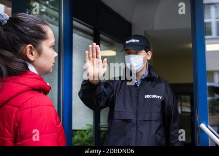 Security Guard In Uniform Und Gesichtsmaske Herstellung Stop Hand Geste Stockfoto