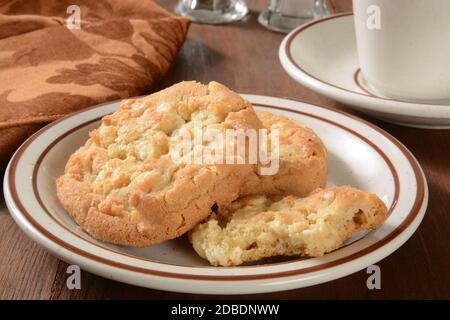 Ein Teller mit Gourmet-Macadamia-Nuss-Cookies mit einer Tasse Kaffee Stockfoto