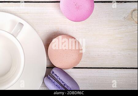 Bunte Makronen in der Nähe von weißen Kaffeetassen in der Nähe von oben Holztisch Stockfoto