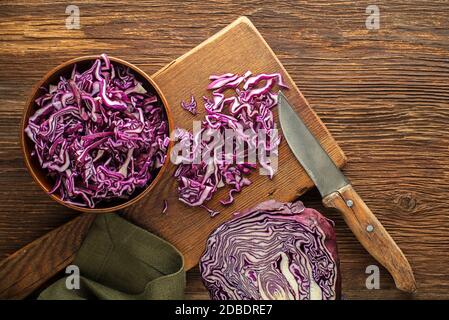 Schneiden Sie Rotkohl auf Schneidebrett auf Holzhintergrund, Draufsicht. Vegetarische, Schlankheits-, Diät-Lebensmittel-Konzept. Stockfoto