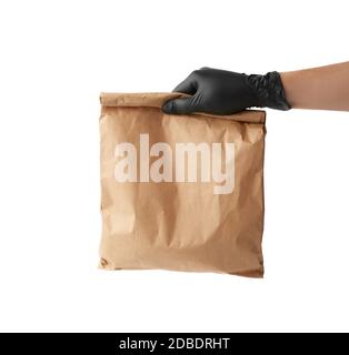 Hand in einem schwarzen Latexhandschuh hält eine volle Papiertüte aus braunem Bastelpapier, das Konzept der ferngesteuerten und kontaktlosen Lebensmittelzustellung, sicheren Eingang von Bestellungen, Stockfoto