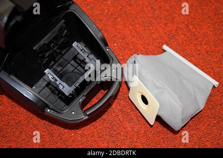 Ein Staubsauger mit einem Satz Bürsten und Beuteln. Ein Staubsauger auf dem roten Teppich. Stockfoto