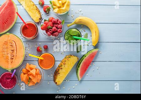 Gesunde Smoothies mit frischen sommerlichen Fruchtzutaten auf blauem Tischhintergrund Stockfoto