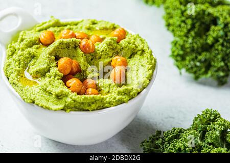 Grüner Grünkohl-Hummus in einer weißen Schale. Vegane Kichererbsen Dip. Gesunde vegetarische Ernährung Konzept. Stockfoto