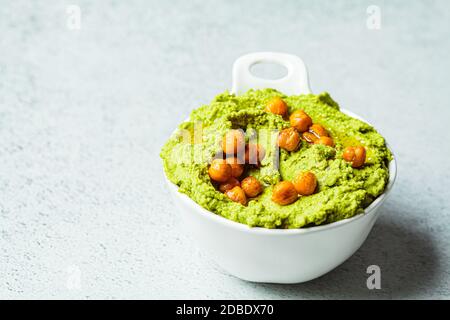 Grüner Grünkohl-Hummus in einer weißen Schale. Vegane Kichererbsen Dip. Gesunde vegetarische Ernährung Konzept. Stockfoto