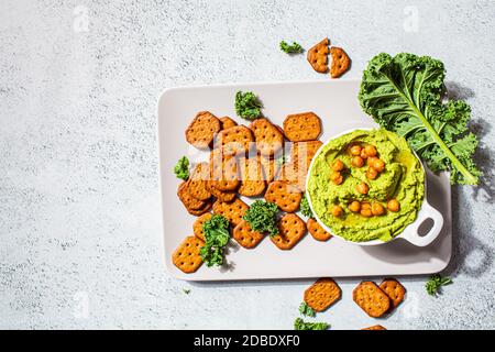 Grüner Grünkohl-Hummus in einer weißen Schale. Vegane Kichererbsen Dip. Gesunde vegetarische Ernährung Konzept. Stockfoto