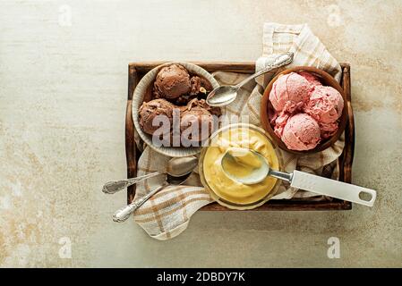 Verschiedene Eisschaufeln mit Schokolade, Erdbeere und Vanille, in Schalen geschöpft Stockfoto