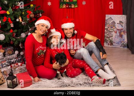 Glückliche Familie von Mutter, Vater und Kind Junge und ihre kleinen Hund sitzt in der Nähe von Weihnachtsbaum Stockfoto