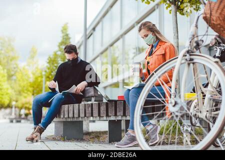 Zwei Studenten lernen, während soziale Distanz auf dem Campus zu halten Stockfoto