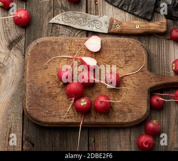 Frischer roter Rettich auf einem braunen Schneidebrett, Salatzutat, Draufsicht Stockfoto