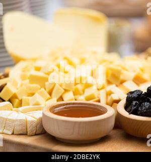Käseplatte mit getrockneten Früchten und Honig. Rustikale Dekoration auf einer Holzplatte. Stockfoto