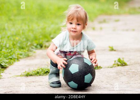 Das niedliche Mädchen spielt mit Fußball auf der Straße. Stockfoto