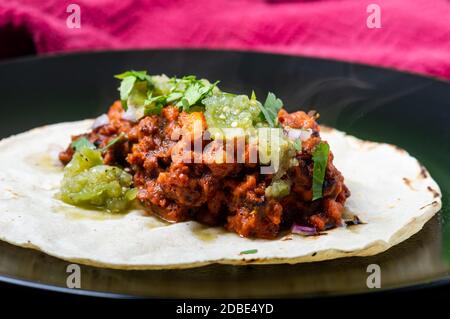 Vegetarische, vegane Tacos al Pastor mit grüner Salsa. Sojaprotein mit al Pastor Marinade gekocht und auf Maistortillas serviert. Stockfoto