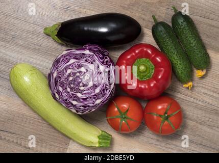 Verschiedene Gemüse (Zucchini, Gurken, Auberginen, Tomaten, Kohl) zusammen auf Holztisch gelegt. Draufsicht. Gemüsehintergrund. Stockfoto