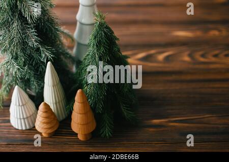 Handgemachte tannenbäume, Miniatur-Keramik und Holzbäume auf rustikalem Tisch. Festliche, moderne Einrichtung, Tischdekoration. Weihnachtsbäume schmücken Stockfoto