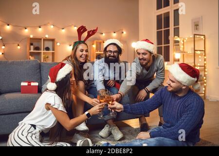 Eine Gruppe von Freunden, die Champagner-Gläser aufziehen und sich gegenseitig wünschen Frohe Weihnachten und ein glückliches neues Jahr Stockfoto