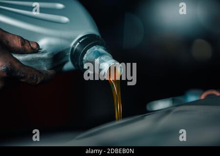 Nahaufnahme von Hand Auto Mechaniker Gießen einen Motor, Motoröl auf das Auto, Reparatur Auto Stockfoto