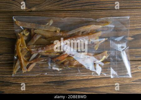 Getrockneter Karpfenfisch klebt in einer transparenten Verpackung Vorspeise zu Bier auf Holzhintergrund. Snack Fisch zu Bier. Nahaufnahme. Stockfoto