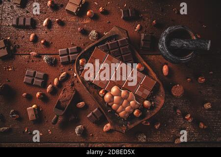 Flacher Lay von dunklen Schokolade Stücke und Bohnen auf Holztisch Stockfoto