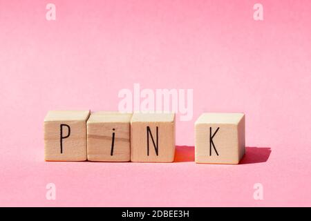 Holzwürfel liegen in einer Reihe auf rosa Hintergrund mit dem Wort Pink, Pastell rosa Natur Konzept close-up Stockfoto