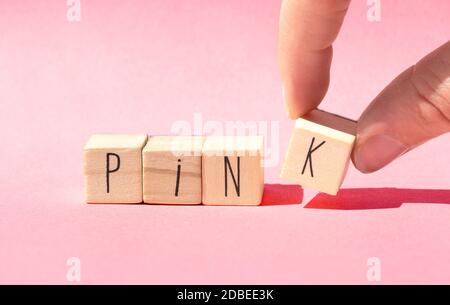 Holzwürfel liegen in einer Reihe auf rosa Hintergrund mit dem Wort Pink, Pastell rosa Natur Konzept close-up Stockfoto