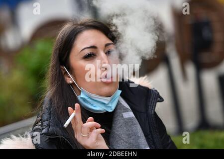München, Deutschland. November 2020. Maskenpflicht in den Fußgängerzonen und öffentlichen Plätzen in München am 17. November 2020. Die junge Frau trägt ihre Alltagsmaske unter ihrem Gesicht und raucht eine Zigarette. MODELL FREIGEGEBEN! Quelle: dpa/Alamy Live News Stockfoto