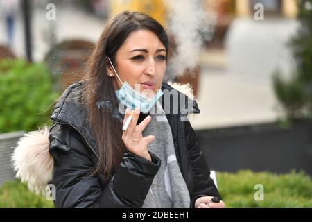 München, Deutschland. November 2020. Maskenpflicht in den Fußgängerzonen und öffentlichen Plätzen in München am 17. November 2020. Die junge Frau trägt ihre Alltagsmaske unter ihrem Gesicht und raucht eine Zigarette. MODELL FREIGEGEBEN! Quelle: dpa/Alamy Live News Stockfoto