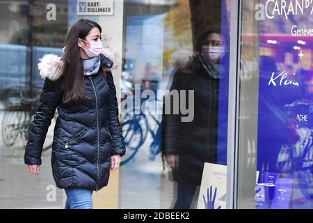 München, Deutschland. November 2020. Themenbild Coronavirus-Pandemie im Herbst/Winter-junge Frau geht mit Gesichtsmaske, Maske an Schaufenster vorbei, MODEL FREIGEGEBEN! Quelle: dpa/Alamy Live News Stockfoto