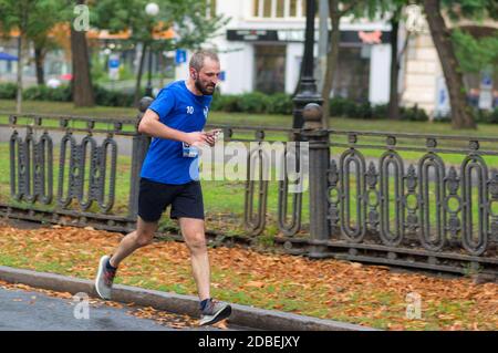 DNIPRO, UKRAINE - 16. SEPTEMBER 2018: Einsamer reifer Mann, der auf einer leeren Stadtstraße während der 21 km langen Strecke des ATB Dnipro Marathon läuft Stockfoto