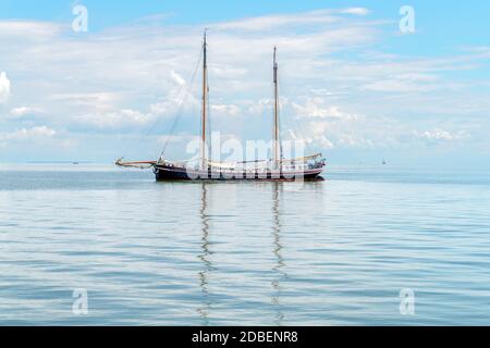 Ein Zweimast-Schiff wird auf der Wasseroberfläche auf See reflektiert Stockfoto