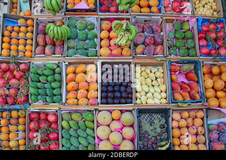 Obst wird in Tablett von Straßenhändler verkauft. Obsttabletts für den Verkauf von Mangos, Granatäpfel, Bananen, Pflaumen, Guave, Orangen. Frisches Obst im Geschäft. Stockfoto