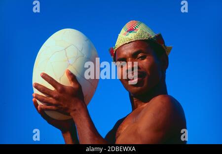 Antandroy Tribal Mann trägt traditionelle Raffia Hut & Holding ein Riesenei des ausgestorbenen Elefantenvogels im Südwesten Madagaskars Stockfoto