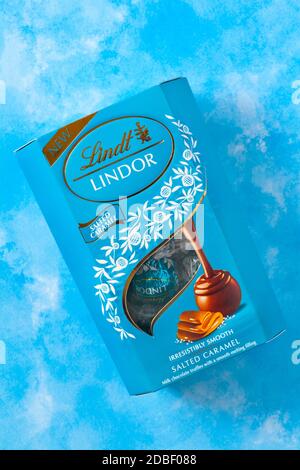 Schachtel Lindt Lindor gesalzenes Karamell unwiderstehlich glatt gesalzenes Karamell Milchschokolade-Trüffel mit einer geschmeidigen schmelzenden Füllung aufgesetzt Blauer Hintergrund Stockfoto