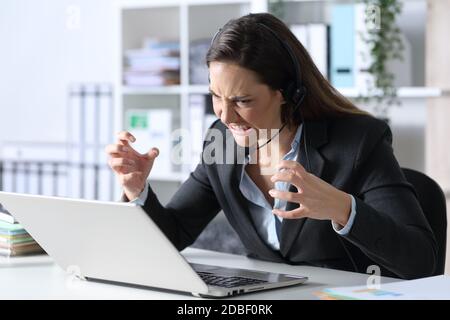 Wütend Telemarketerin Frau Blick auf Laptop sitzt auf einem Schreibtisch im Büro Stockfoto