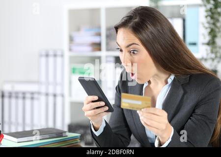 Überraschte die Exekutive, die mit dem Smartphone und Kreditkarte auf dem Schreibtisch im Büro bezahlt Stockfoto