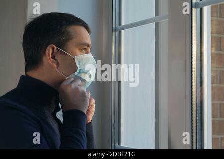 Schutz vor einer Pandemie des Coronavirus beim Ausgehen. Der Mensch geht in einer medizinischen Maske spazieren. Porträt des Mannes in Schutzmaske. Junger Mann setzt auf ein Stockfoto