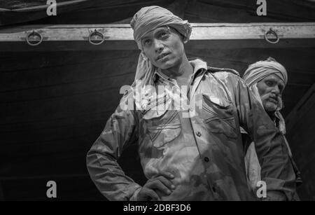 Arbeiter, die mit schweren Zementsäcken vom Eisenbahnzug zum wartenden Lastwagen, Mathura, Uttar Pradesh, Indien, beschäftigt sind. Stockfoto