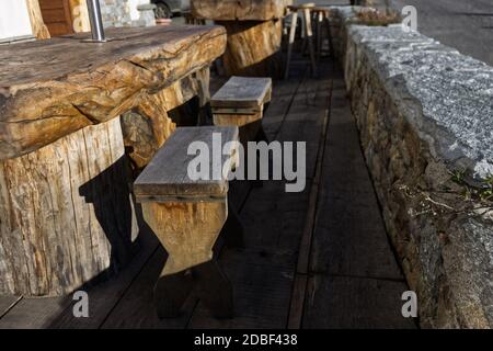 Typisch italienische Alpenlandschaft: Bänke und Tische aus einem einzigen Holzstamm vor einem Häuschen geschnitzt. Stockfoto