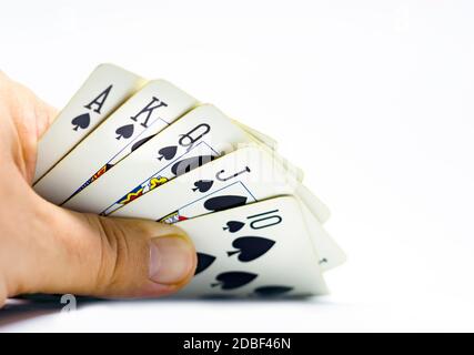 Ein Spieler enthüllt einen königlichen Flush in Pik. Glücksspiel und Glück. Entscheidungen und Risiken. Isoliert auf weißem Hintergrund Stockfoto