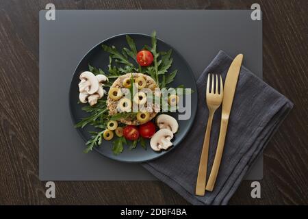 Gesundes Quinoa-Gericht. Diätetischer Salat mit Quinoa, Pilzen, Rucola und Oliven. Gesundes Essen, vegetarisches Menü. Draufsicht. Einstellungstabelle. Stockfoto