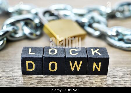 Buchstabenwürfel bilden das Wort Lockdown vor Eisenkette und Vorhängeschloss, Corona Lockdown Stockfoto