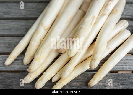 Frischer weisser Spargel der Saison auf rustikalen grauen Holzplanken. Hintergrund für ein gesundes Ernährungskonzept mit Platz für Text. Stockfoto