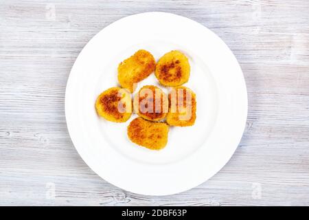 Draufsicht auf die Portion gebratener Hähnchennuggets auf weißem Teller auf grauem Holzbrett Stockfoto