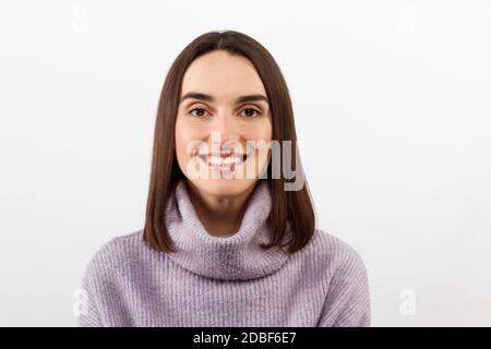 Charmante Mädchen in einem lila Pullover im Studio auf Ein weißer Hintergrund lächelt wunderschön und sehr glücklich Stockfoto