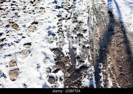 Draufsicht auf nassen schmutzigen Weg mit Schnee nach dem letzten Schneefall im Stadtpark am sonnigen Frühlingstag bedeckt Stockfoto